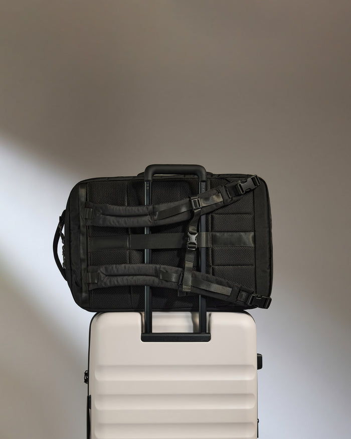 a black bag on top of a white suitcase