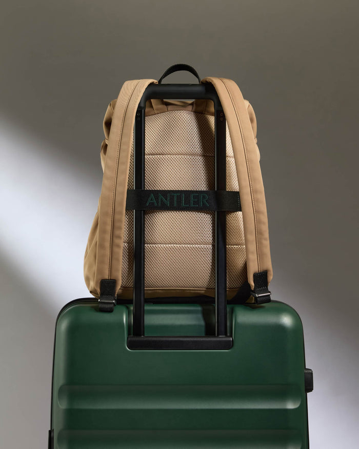 a backpack on top of a green suitcase