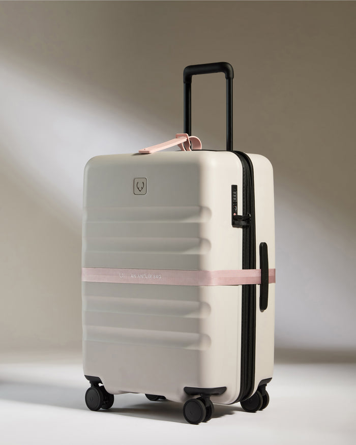 a white suitcase with a pink ribbon around it